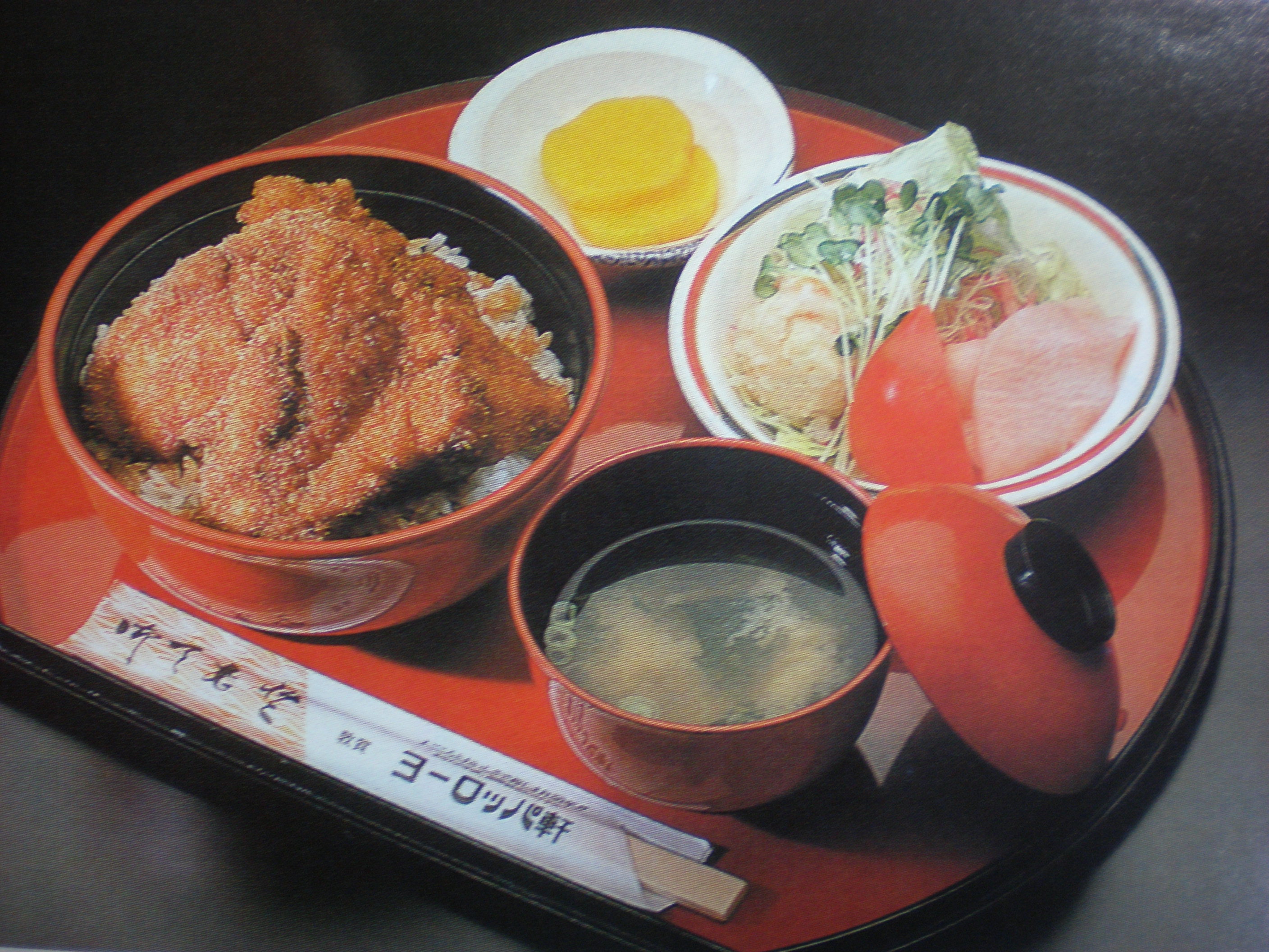 赤いお盆にのったソースカツ丼とみそ汁、サラダ