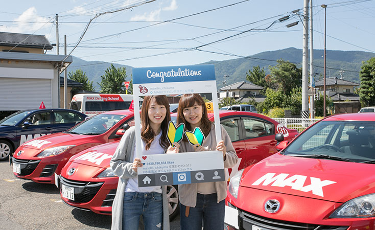 MAXドライビングスクール千曲の卒業記念パネルと教習車